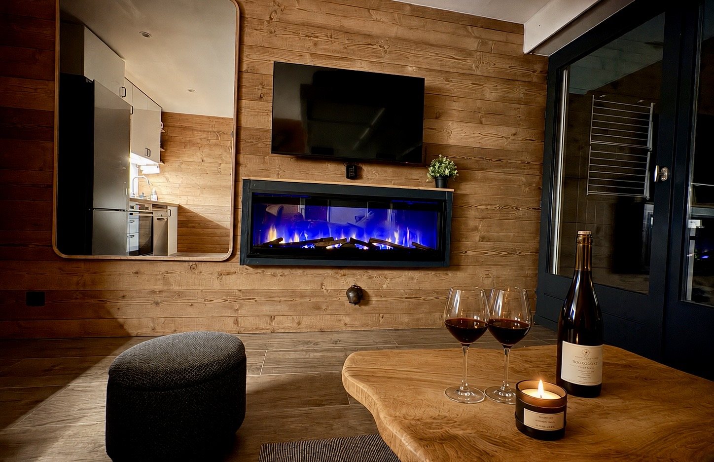 Soirée au coin de la cheminée, deux verres de vin devant le mur en bois — le cocon du studio aux Contamines-Montjoie